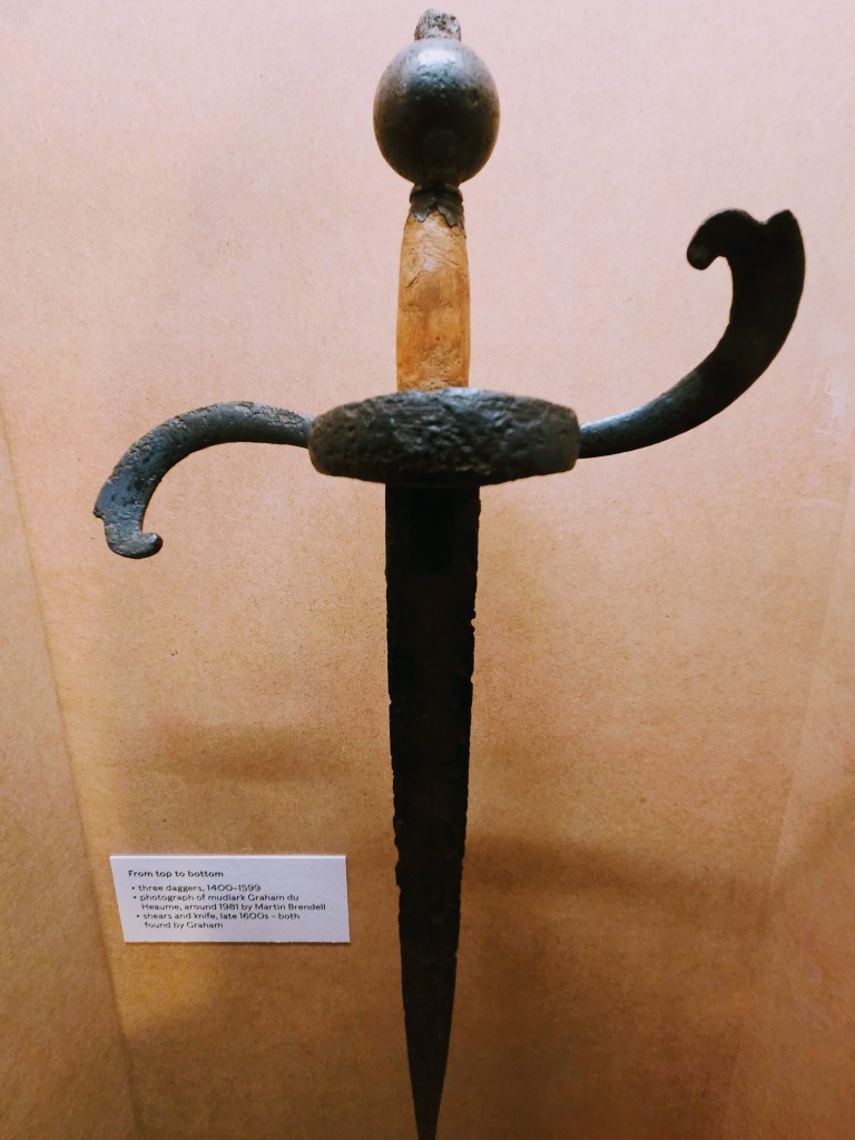An antique sword with a leather handle and an ornate guard, displayed against a brown background with an informational label underneath.